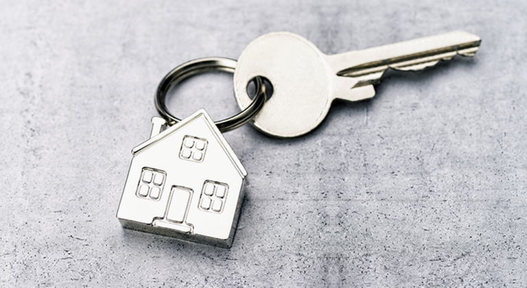 Nyckel fastsatt på en nyckelring som föreställer ett hus.