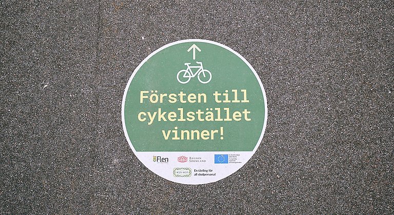 Bild på en skylt på vägen där det står "försten till cykelstället vinner!"